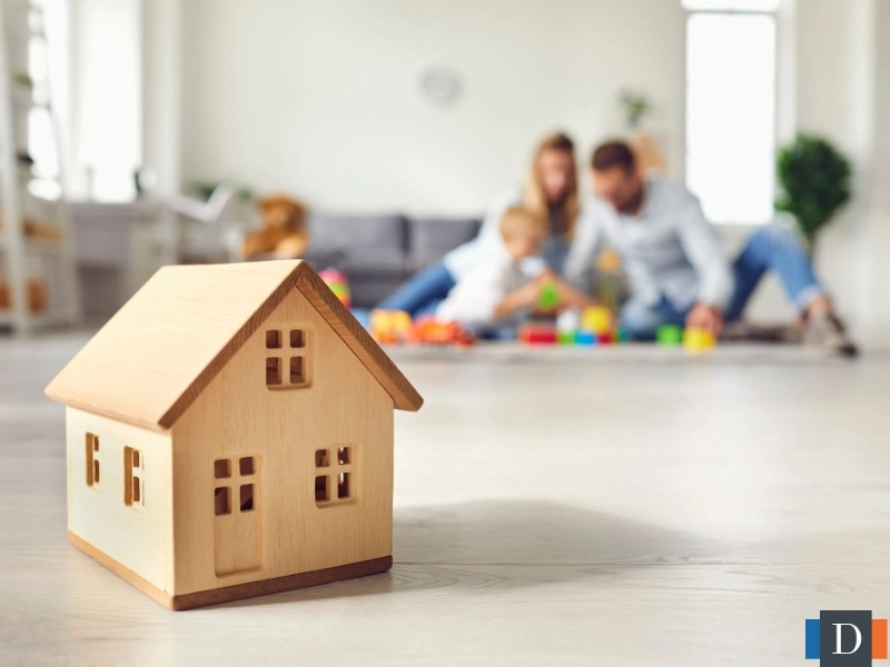 Parents playing with their child with a figure of a home in the forefront. This image is for the blog titled "What is Estate Administration vs Letter of Testamentary in NC?" 