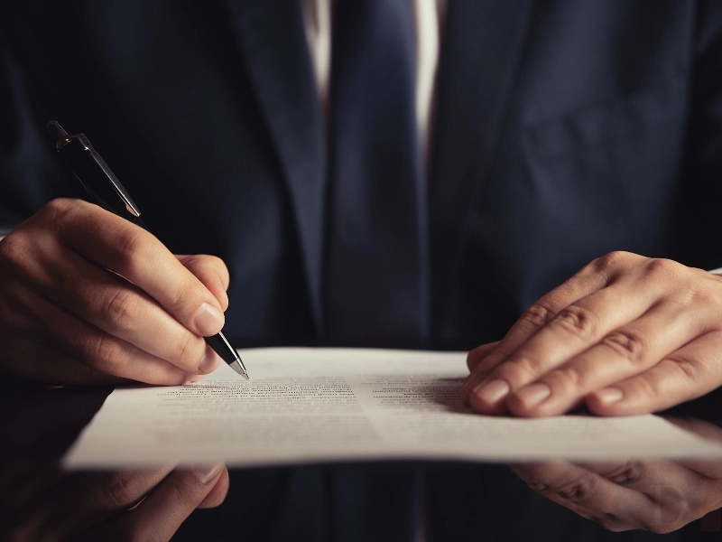 Masculine hands signing a document. Estate planning attorney in Cary NC