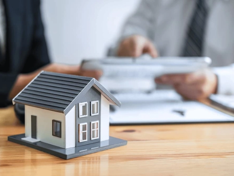 A Cary estate administration attorney reviews a document with a client. House figure on desk.